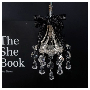 Close-up of a mini crystal chandelier ornament with silver glitter and a black bow