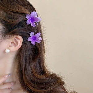 Detail view of two purple gradient sunflower hair claws worn on a model side profile