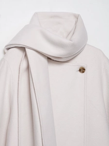 Close-up of cream wool blend coat with matching scarf collar and amber button detail