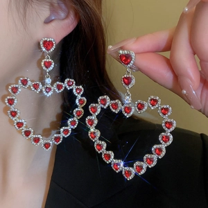 Close-up of red rhinestone heart earrings featuring luxury sparkling crystal accents