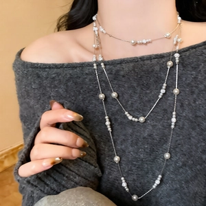 Detail of layered pearl necklace with diamond-studded beads over a grey sweater