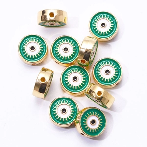 Detailed macro view of golden evil eye beads with green enamel for DIY jewelry making