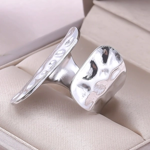 Macro view of wide silver stainless steel ring with hammered texture and open band design