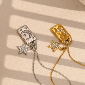 Detail of silver and gold square moon star pendants with crystals in sunlight