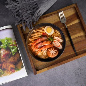 Japanese style vintage ceramic ramen bowl with toppings on a wooden tray with a cookbook