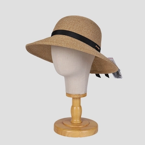 Detail of woven straw sun hat showing the black ribbon band and metal buckle accent