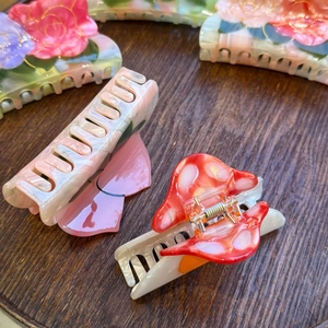Detail of acetate flower hair claws with vintage double lotus patterns on a wooden tray