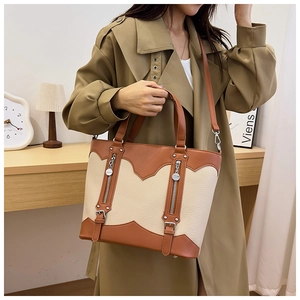 Detail of two-tone tote bag in brown and off-white leather with metal zip accents