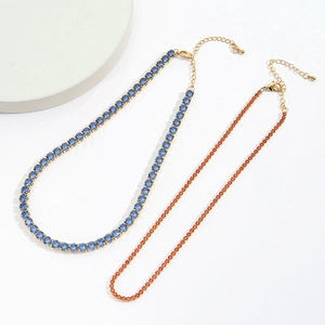 Detail view of gold-plated tennis necklaces featuring blue and orange cubic zirconia stones