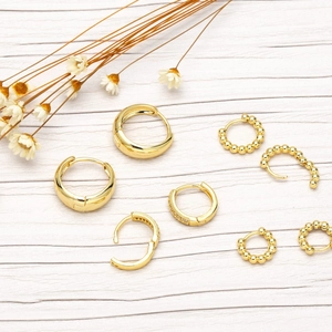 Detailed view of assorted chunky gold hoops and beaded earring sets on wooden background