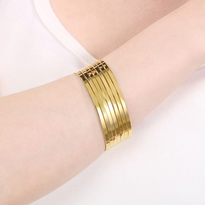 Close-up of a wide layered gold-plated titanium steel bangle worn on a female wrist