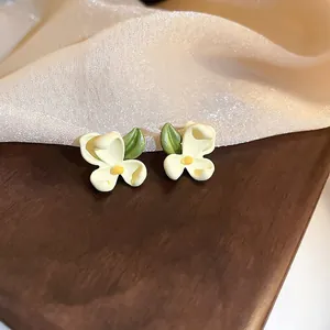 Elegant cream white flower stud earrings with yellow center and green leaf detail