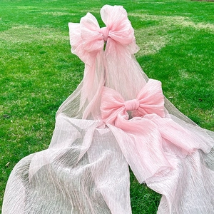Detail of pink pleated fabric bows with long ribbons on green grass background