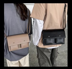 Close-up of black and brown vintage messenger bags featuring dual front pockets and flap