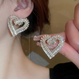 Boucles d'oreilles cœur évidé en or avec zircons brillants portées par un mannequin