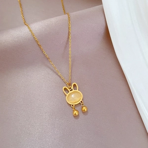 Detail of a gold rabbit pendant necklace with opal stone on a silk background