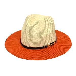 Détail d'un chapeau de paille bicolore avec bande noire et boucle dorée élégante
