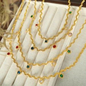 Elegant gold twisted rope necklace featuring multi-colored gemstones in a velvet jewelry box