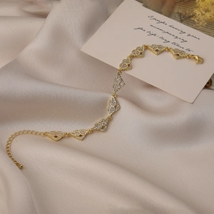 Elegant gold-plated heart and wing bracelet with cubic zirconia on silk background