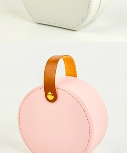 Detail of round portable jewelry box with leather handle and gold rivet accents