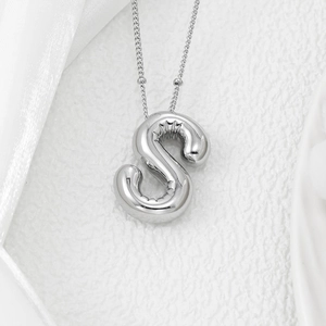 Macro shot of puffy balloon letter S pendant with silver polished finish on beaded chain
