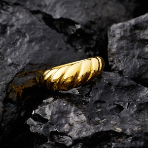 Minimalist gold croissant dome ring crafted in polished titanium steel on a black rock
