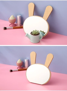 Detail of wooden bunny-shaped desk mirror with natural texture on a pastel background