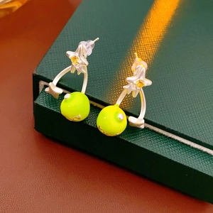 Detail of silver star earrings with green bead drops on a luxury gift box edge