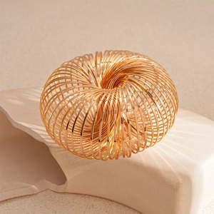 Macro shot of geometric gold hollow spring flow ring on a textured stone pedestal