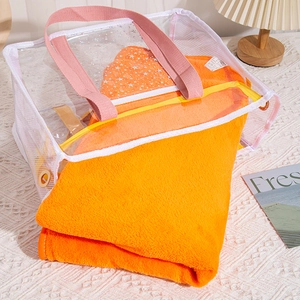 Detail of transparent PVC mesh beach bag with pink handles and orange plush towel inside