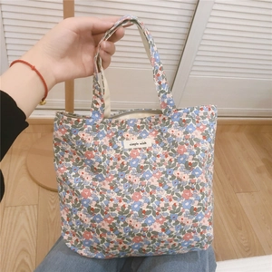 Dettaglio della piccola borsa in tela a fiori con zip ed etichetta simple wish