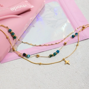 Détail de colliers superposés en acier inoxydable 18K avec perles bleues et étoile
