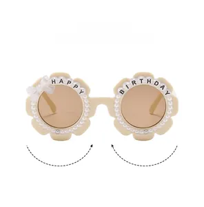 Macro shot of flower-shaped kids sunglasses with pearls and Happy Birthday text