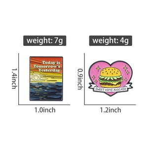 Detail showing dimensions of sunset landscape and heart burger enamel pins on white background