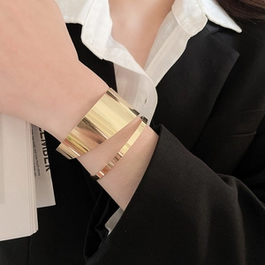 Polished gold bangles set featuring a wide mirror cuff and a minimalist slim ring detail