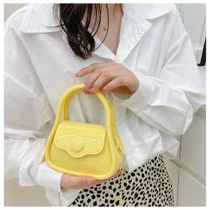 Detail of yellow mini jelly handbag with golden chain strap and glossy finish