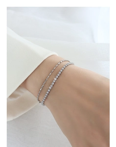 Detail of silver double-layer bracelet with sparkling zircons worn on a female wrist
