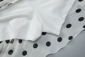Close-up of chiffon polka dot fabric with white safety lining and stitching details