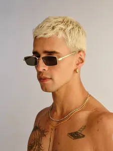 Detalle de gafas de sol cuadradas de metal dorado con lentes oscuras en modelo masculino
