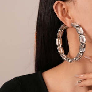 Boucles d'oreilles créoles argentées avec strass en acrylique portées par un mannequin