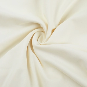 Macro detail of soft cream-colored knit fabric showing textured folds and draping quality