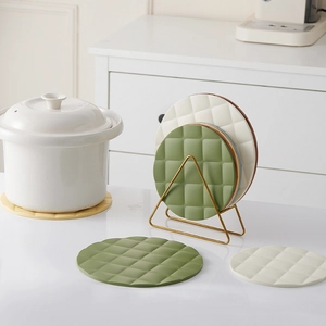 Green and cream round silicone trivets with diamond pattern on a gold metal storage rack