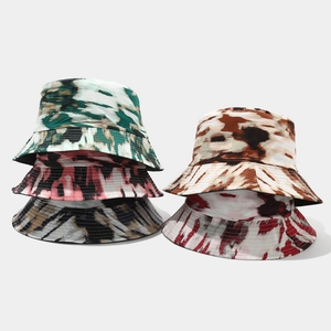 Detail view of five tie-dye bucket hats in various patterns and colors on plain background