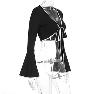 Detail of black crop top with bell sleeves, contrast white trim and front lace-up closure