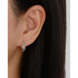 Macro detail of silver layered wave ear cuffs on ear with polished finish and cutout design