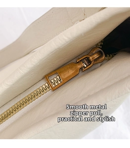 Macro shot of a smooth bronze zipper head on white lychee grain leather tote bag