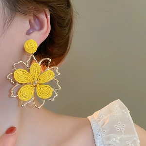 Close-up of yellow woven petal flower earrings on model showcasing artisanal details