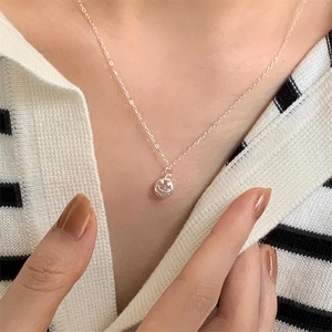 Close-up of minimalist silver smiley face pendant necklace worn by a model