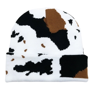 Winter knitted beanie with black, white and brown cow print pattern on a white background