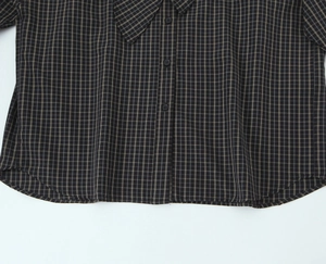 Detail of dark grey plaid cotton shirt featuring fine button-down closure and woven texture